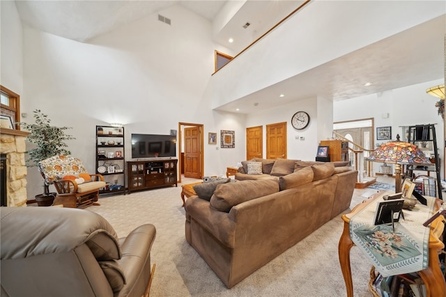 carpeted living room with a stone fireplace and a towering ceiling