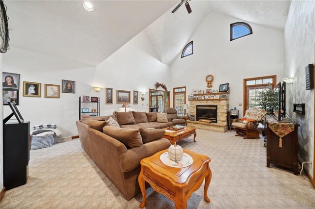 living room with a stone fireplace, light colored carpet, high vaulted ceiling, and ceiling fan