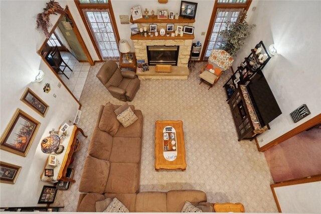 living room with a stone fireplace and a towering ceiling