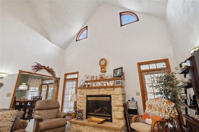 living room with a stone fireplace and high vaulted ceiling