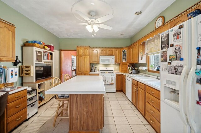 kitchen featuring ceiling fan, light tile patterned floors, a breakfast bar, a kitchen island, and white appliances