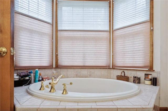 bathroom featuring tiled bath and a wealth of natural light