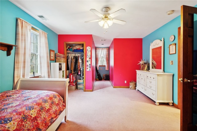 bedroom featuring a spacious closet, light carpet, a closet, and ceiling fan