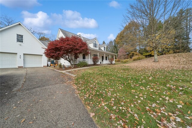 view of front facade featuring covered porch, a front yard, and a garage