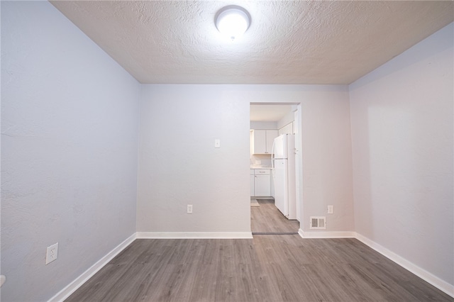 spare room featuring wood-type flooring and a textured ceiling