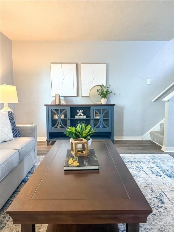 living room featuring baseboards, wood finished floors, and stairs
