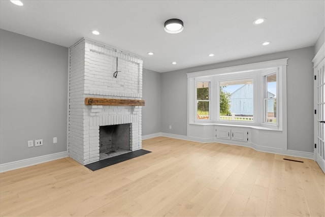 unfurnished living room with light hardwood / wood-style floors and a brick fireplace