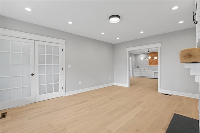 unfurnished living room with a notable chandelier and light wood-type flooring