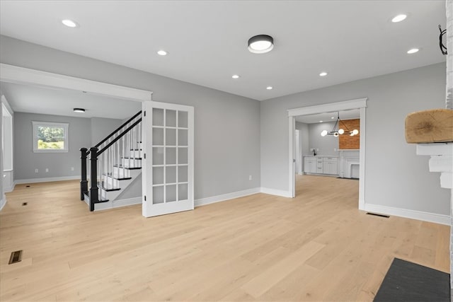 unfurnished living room with a notable chandelier and light wood-type flooring