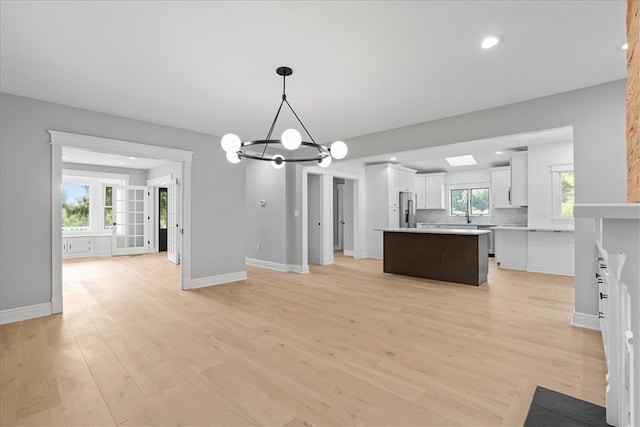 kitchen with white cabinetry, a center island, light wood-type flooring, and stainless steel fridge