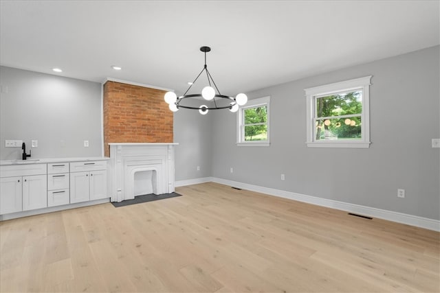 unfurnished living room featuring sink, a chandelier, and light hardwood / wood-style flooring