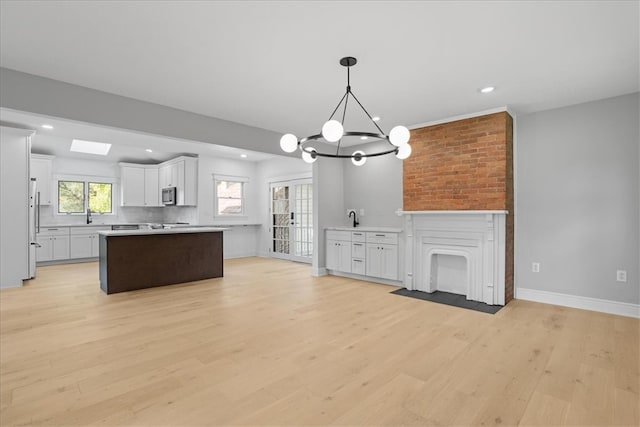 kitchen with light hardwood / wood-style flooring, a notable chandelier, stainless steel appliances, and white cabinetry