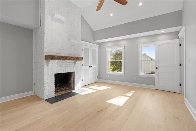 unfurnished living room with ceiling fan, high vaulted ceiling, light wood-type flooring, and a brick fireplace