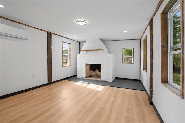 unfurnished living room with hardwood / wood-style floors, crown molding, a fireplace, and a wall mounted air conditioner