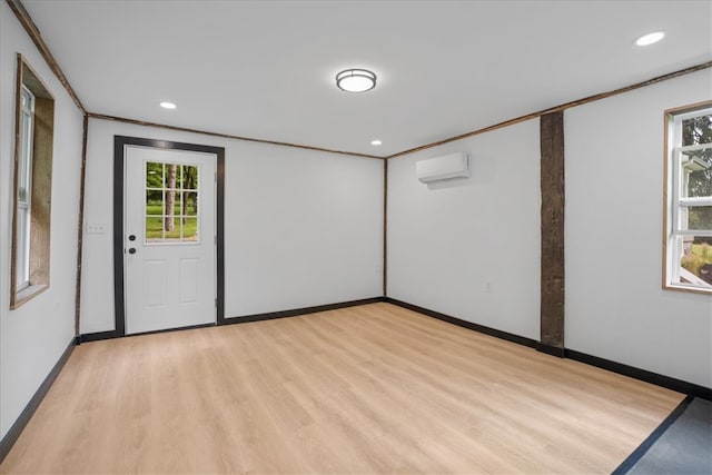 empty room featuring crown molding, light hardwood / wood-style flooring, and a wall mounted air conditioner