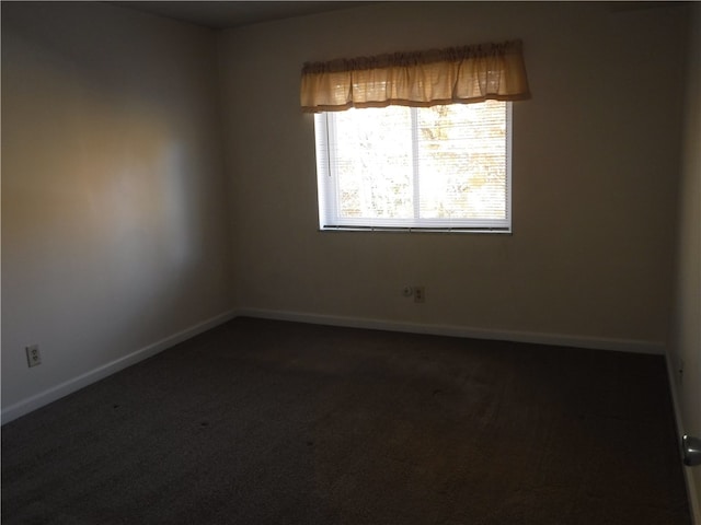 spare room featuring dark carpet