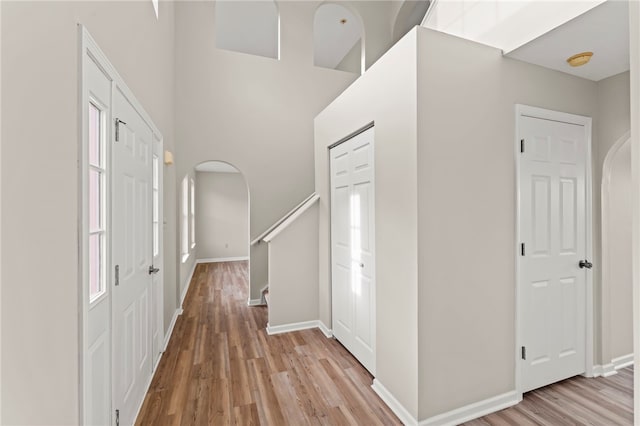 foyer entrance featuring a towering ceiling and light wood-type flooring