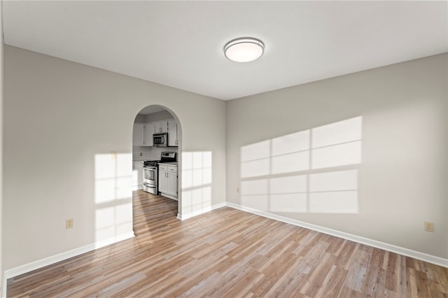 1315 Lucia Dr, Canonsburg, PA 15317 - unfurnished living room with arched walkways, light wood finished floors, and baseboards