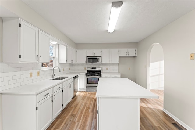 kitchen with light hardwood / wood-style floors, white cabinetry, stainless steel appliances, and sink