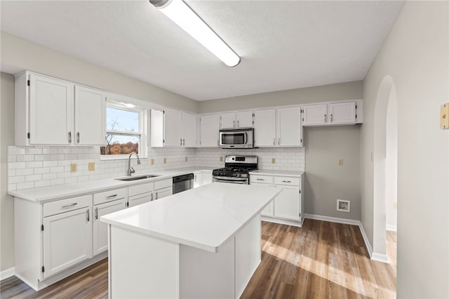 kitchen featuring appliances with stainless steel finishes, white cabinets, sink, and a kitchen island