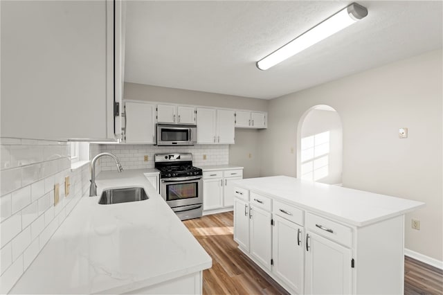 kitchen with stainless steel appliances, sink, a kitchen island, and white cabinets