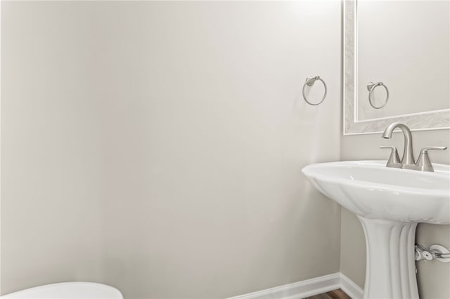 bathroom with toilet, wood-type flooring, and sink