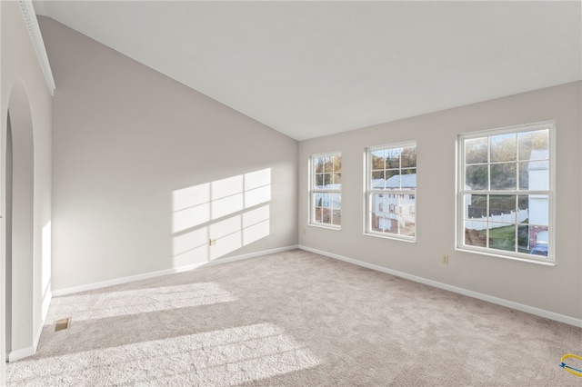 carpeted spare room featuring vaulted ceiling