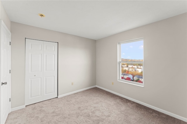 unfurnished bedroom featuring a closet and light colored carpet