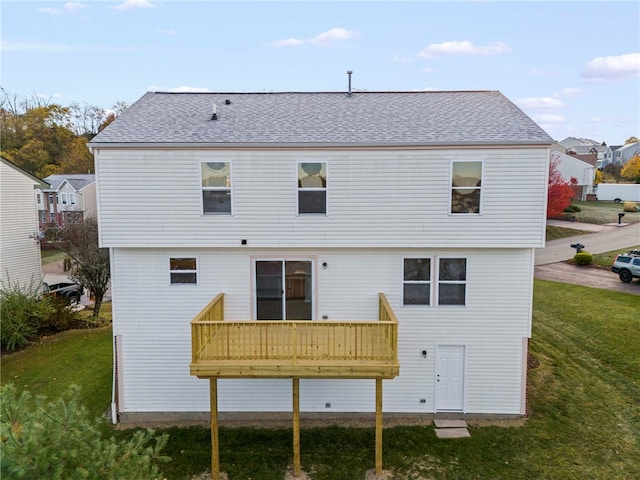 rear view of house featuring a deck and a lawn