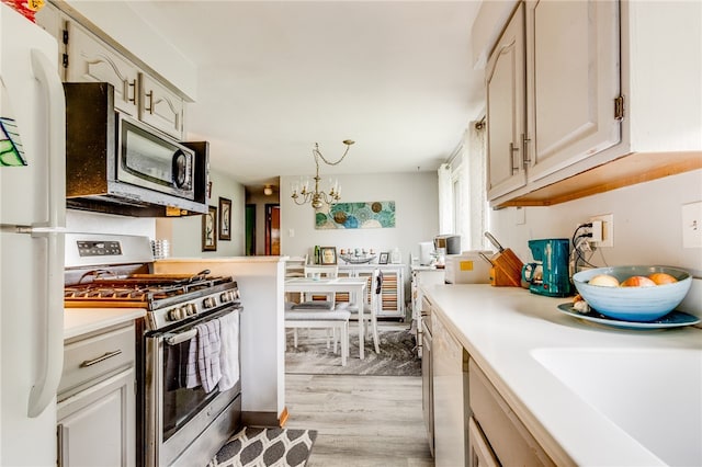 kitchen with sink, a notable chandelier, appliances with stainless steel finishes, and light hardwood / wood-style flooring