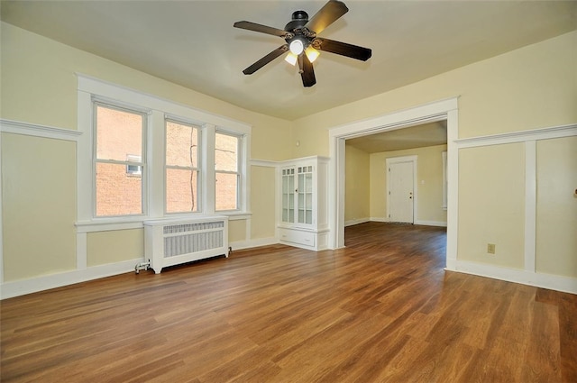 empty room featuring hardwood / wood-style flooring, radiator, and ceiling fan