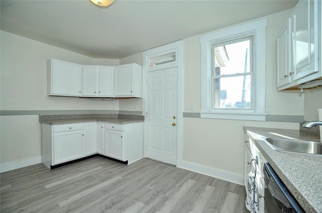 kitchen with light hardwood / wood-style flooring, sink, stainless steel dishwasher, and white cabinets