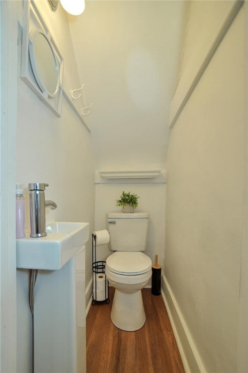 bathroom featuring sink, toilet, wood-type flooring, and lofted ceiling