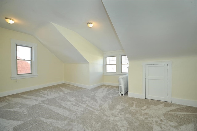 additional living space with lofted ceiling, light colored carpet, radiator, and plenty of natural light