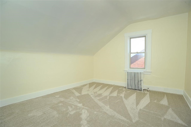 additional living space with lofted ceiling, radiator heating unit, and carpet flooring