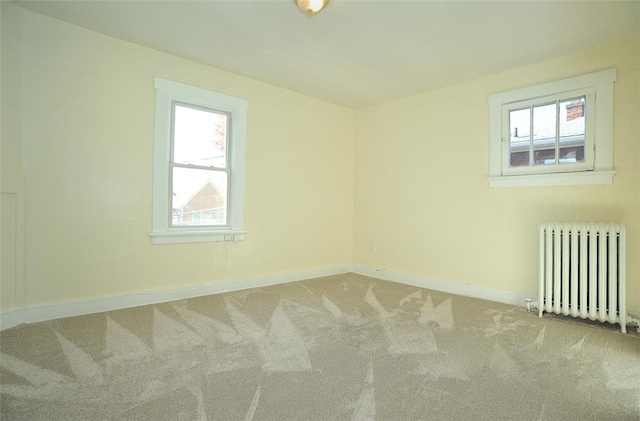 carpeted empty room with radiator heating unit and a healthy amount of sunlight