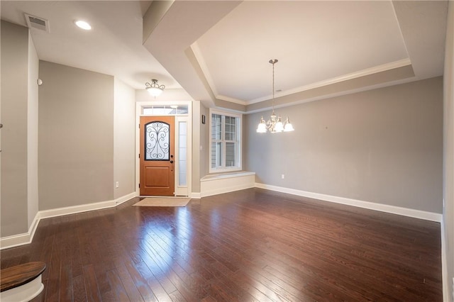 foyer featuring dark hardwood / wood-style floors, a raised ceiling, and a notable chandelier