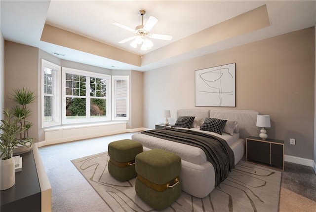 carpeted bedroom featuring a tray ceiling and ceiling fan