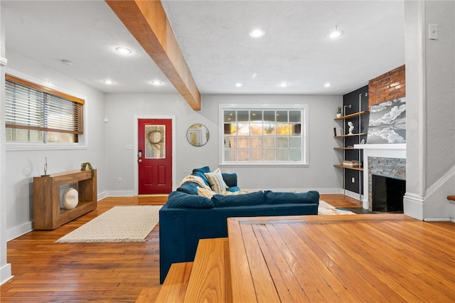 living room featuring hardwood / wood-style flooring, beamed ceiling, and a fireplace