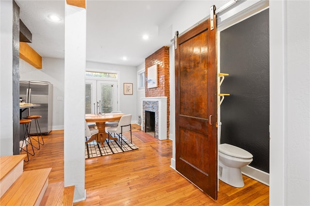 interior space featuring light hardwood / wood-style floors, a brick fireplace, and a barn door