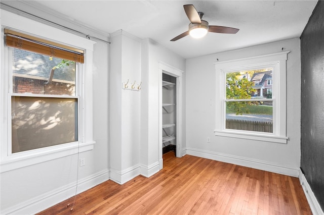 unfurnished bedroom with a closet, multiple windows, light wood-type flooring, and ceiling fan