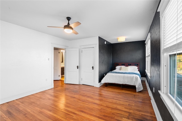 unfurnished bedroom featuring multiple windows, wood-type flooring, and ceiling fan