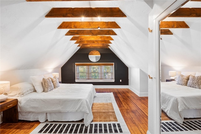 bedroom featuring dark wood-type flooring and vaulted ceiling with beams