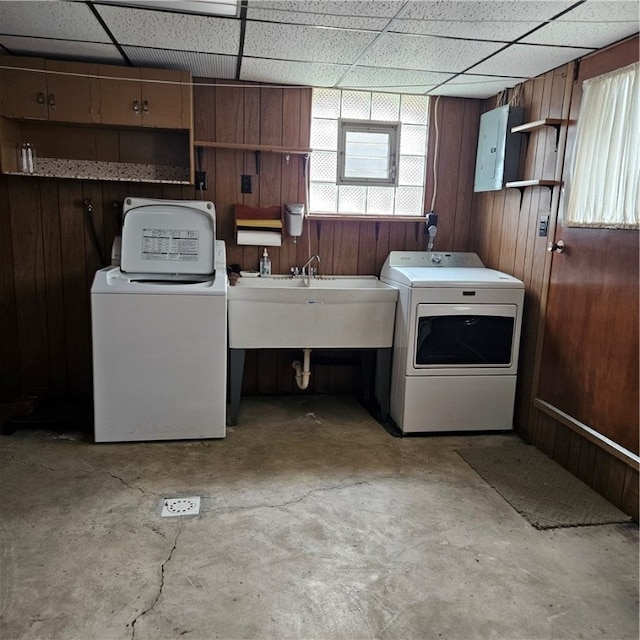 laundry room featuring electric panel, wooden walls, sink, and washing machine and clothes dryer