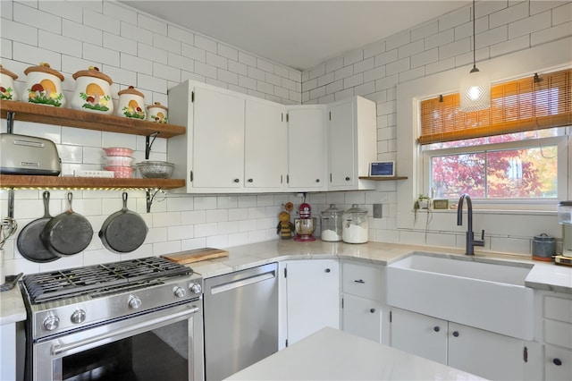 kitchen with decorative backsplash, white cabinets, hanging light fixtures, sink, and stainless steel appliances