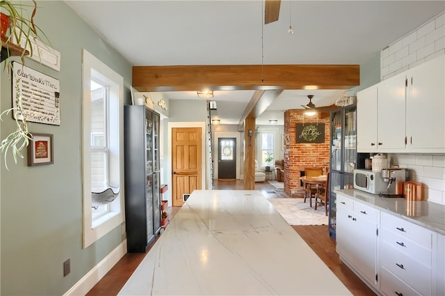 kitchen with tasteful backsplash, white cabinetry, ceiling fan, beamed ceiling, and dark hardwood / wood-style floors