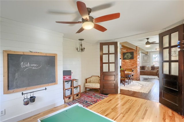 playroom with wood-type flooring and ceiling fan with notable chandelier