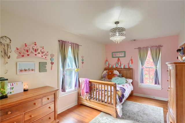 bedroom with light hardwood / wood-style flooring and a chandelier