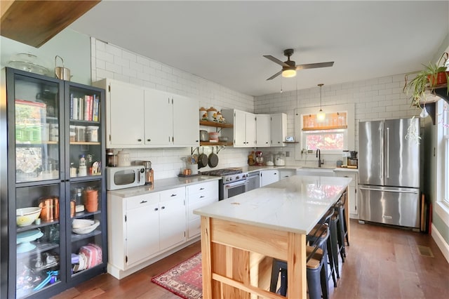 kitchen with sink, premium appliances, dark hardwood / wood-style flooring, and white cabinets