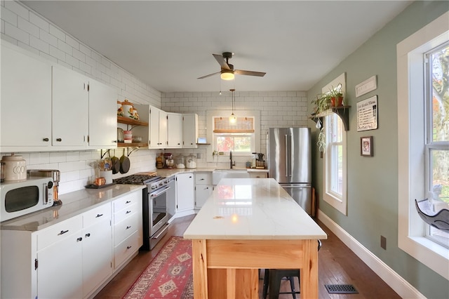 kitchen with appliances with stainless steel finishes, sink, a kitchen island, hardwood / wood-style floors, and white cabinetry